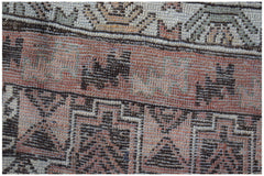 A close-up of an Afghan Baluch rug featuring geometric patterns in shades of red, brown, and cream.