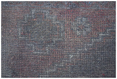 A close-up view of a handmade Afghan Baluch rug featuring a dark, geometric wool pattern.