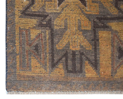 A close-up of a handmade Afghan Baluch rug featuring geometric patterns in brown and gold wool.