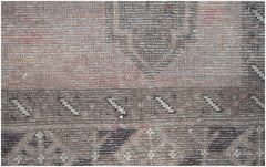 A close-up view of a handmade Afghan Baluch rug featuring geometric patterns in earthy tones.