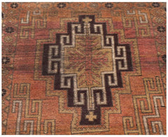 Handmade Afghan Baluch rug featuring a geometric diamond medallion in shades of orange and brown.