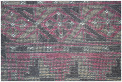 A close-up of a handmade Afghan Baluch rug featuring geometric diamond and step patterns in wool.