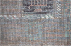 A close-up of a handmade Afghan Baluch rug featuring geometric patterns in brown and muted green.