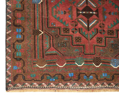 Handmade Afghan Pashm rug featuring a geometric tribal pattern in red, brown, and blue wool.
