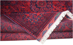 A handmade Afghan Biljik rug featuring deep red and blue geometric patterns with white fringe.
