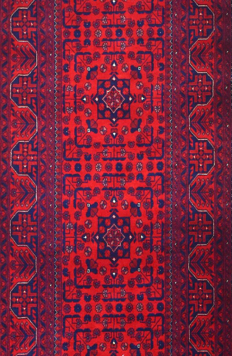 An Afghan Biljik runner featuring intricate geometric patterns in deep red and blue wool.