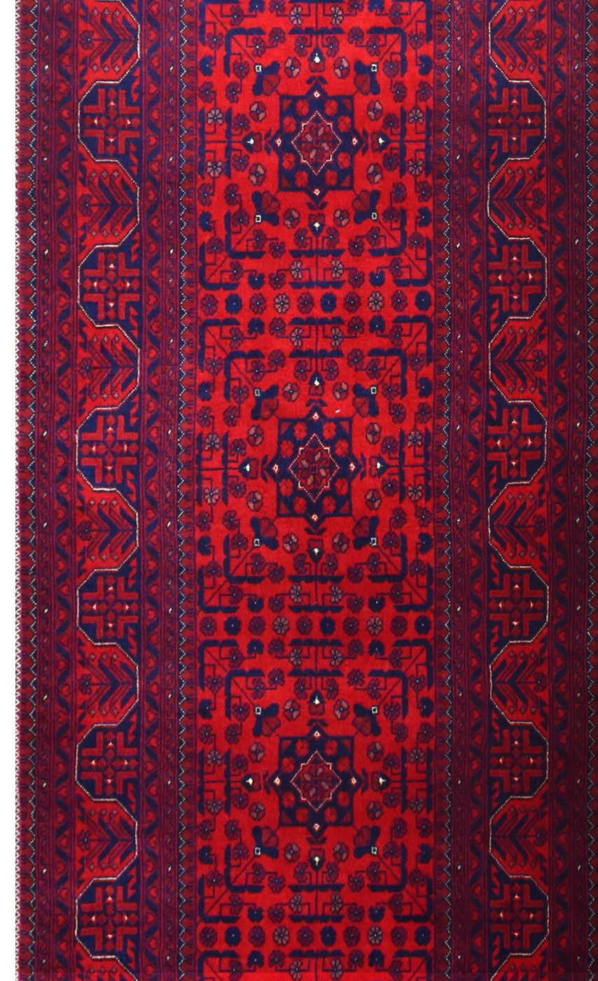 A handmade Afghan Biljik runner featuring intricate geometric patterns in deep red and blue wool.