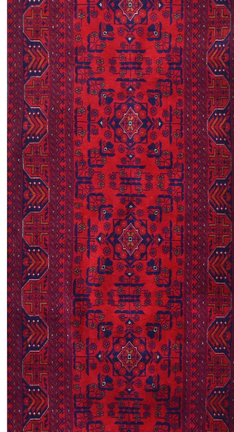 An Afghan Biljik runner rug featuring intricate geometric patterns in deep red and blue wool.