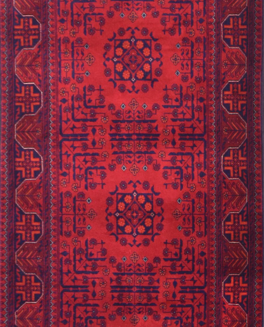 An Afghan Biljik runner featuring intricate geometric patterns in deep red and blue wool.
