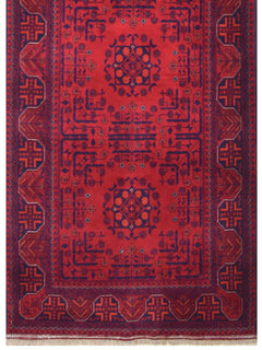 An Afghan Biljik runner rug featuring a deep red field with intricate blue geometric floral motifs.