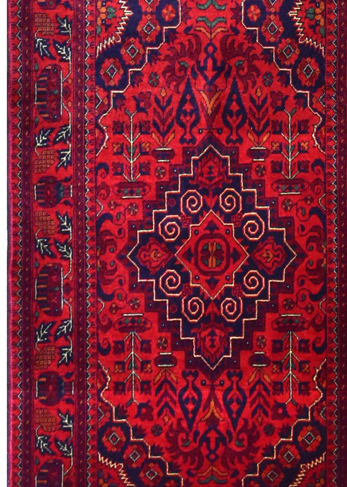 An Afghan Biljik runner featuring a deep red background with intricate blue geometric patterns.