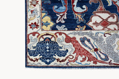 A corner detail of a handwoven Afghan Chobi rug featuring intricate floral patterns in blue and red.