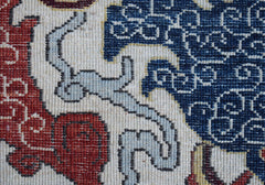 A close-up of a handwoven Afghan Chobi rug featuring intricate blue, red, and cream patterns.