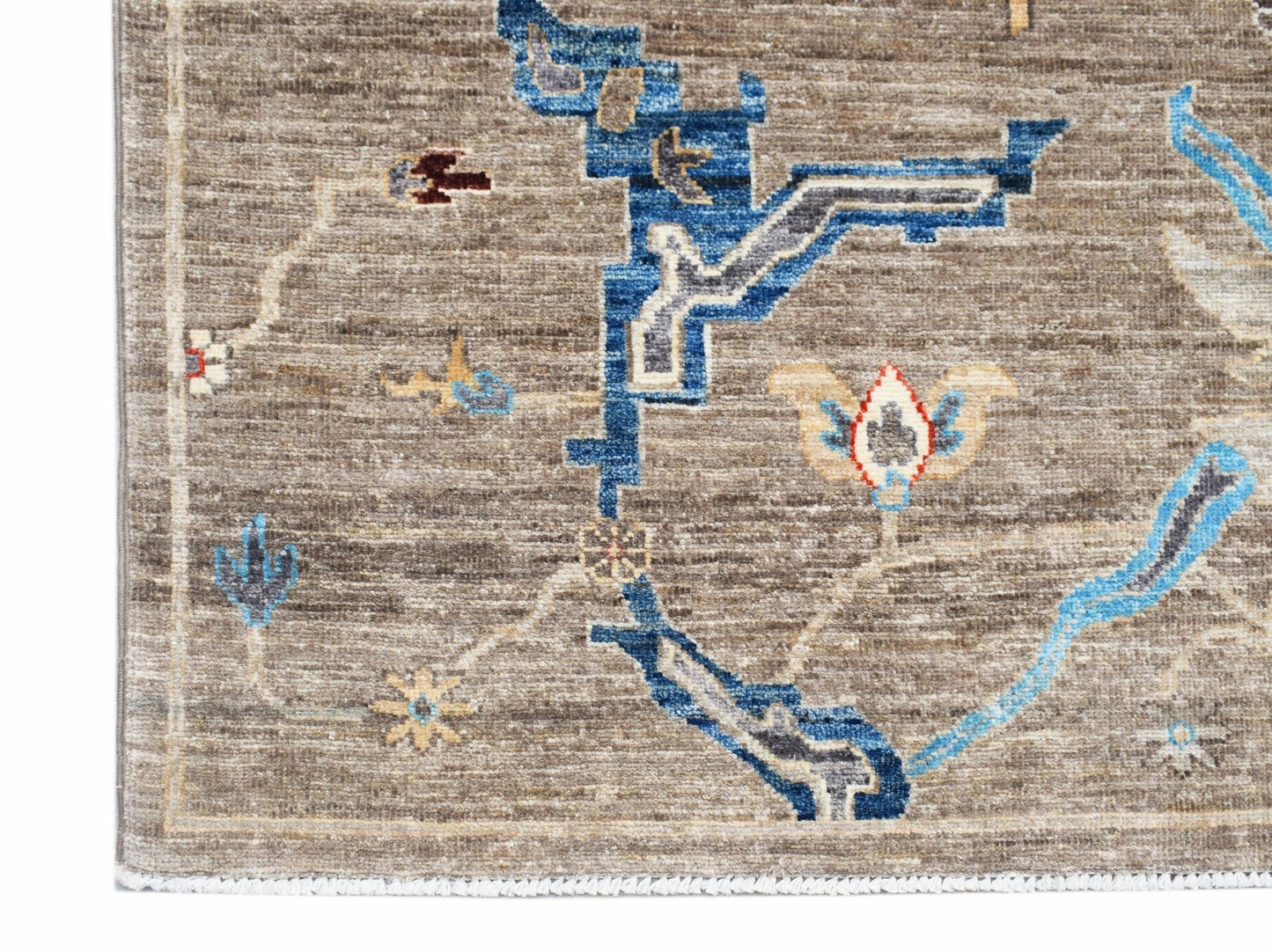 A handwoven Afghan Chobi rug featuring blue geometric and floral patterns on a brown wool field.