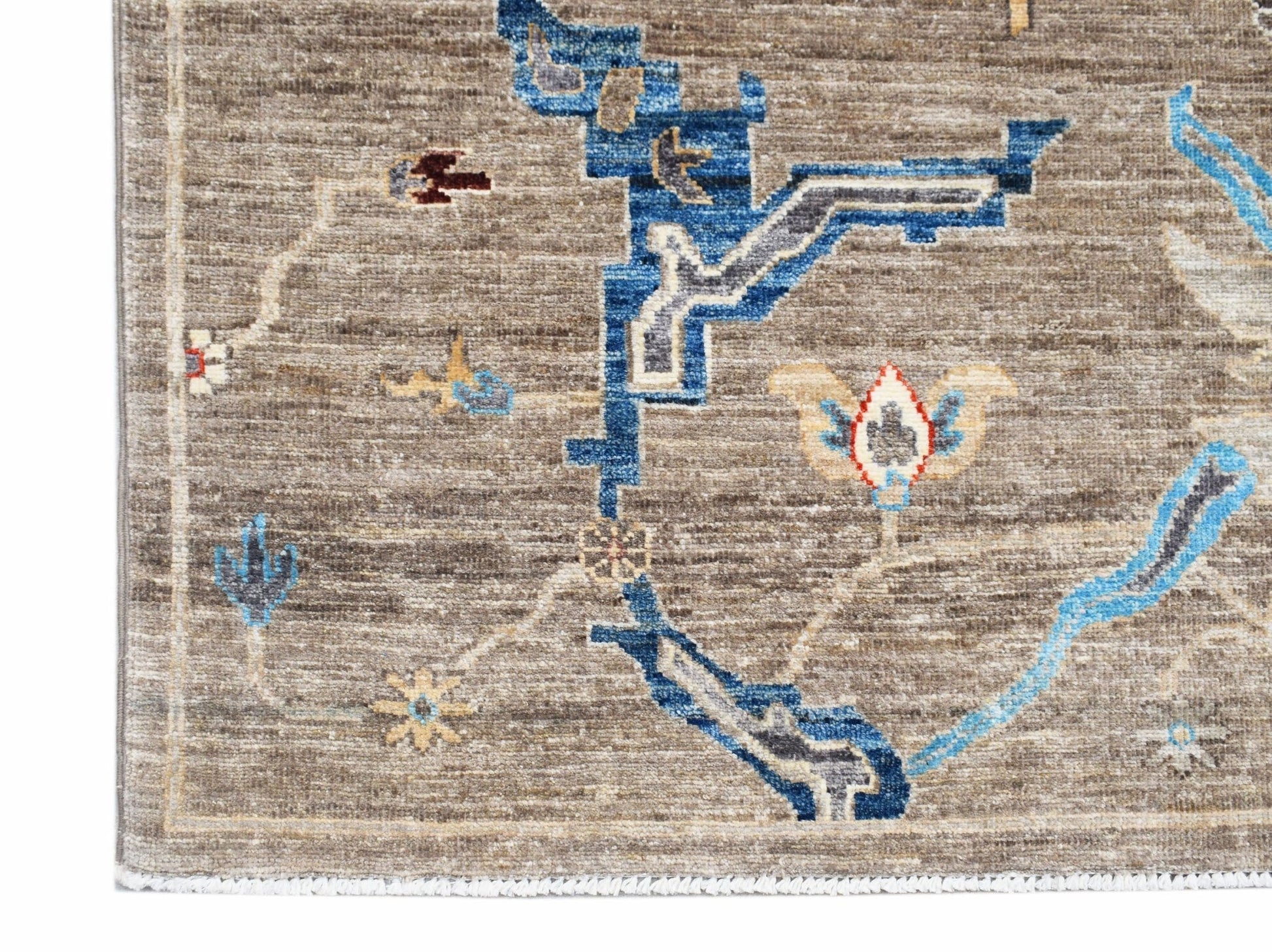 A handwoven Afghan Chobi rug featuring blue geometric and floral patterns on a brown wool field.