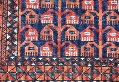 A close-up of an Afghan Chobi rug featuring a geometric pattern of red and blue motifs.