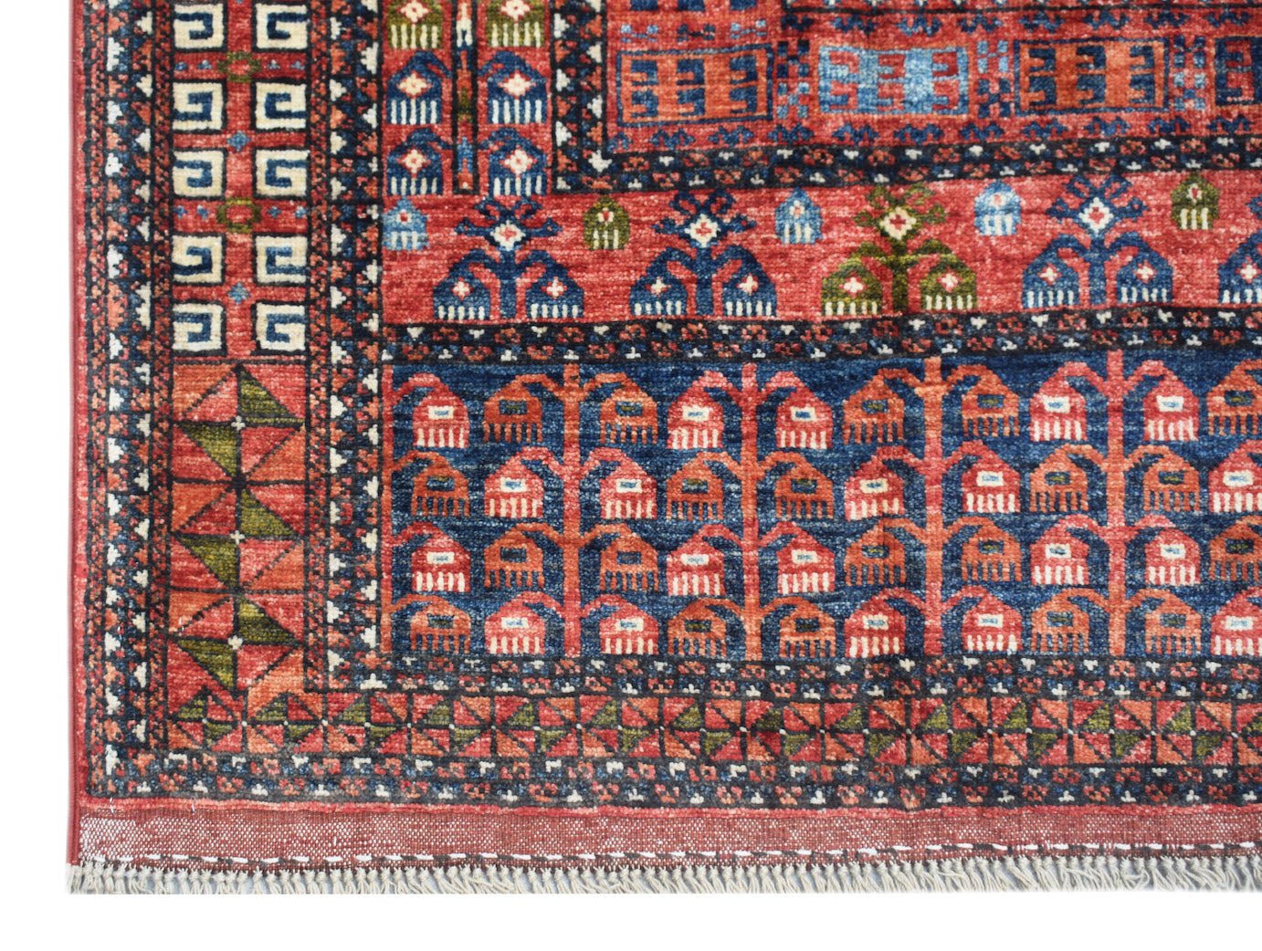 A handwoven Afghan Chobi rug featuring a traditional red and blue geometric Engsi pattern.