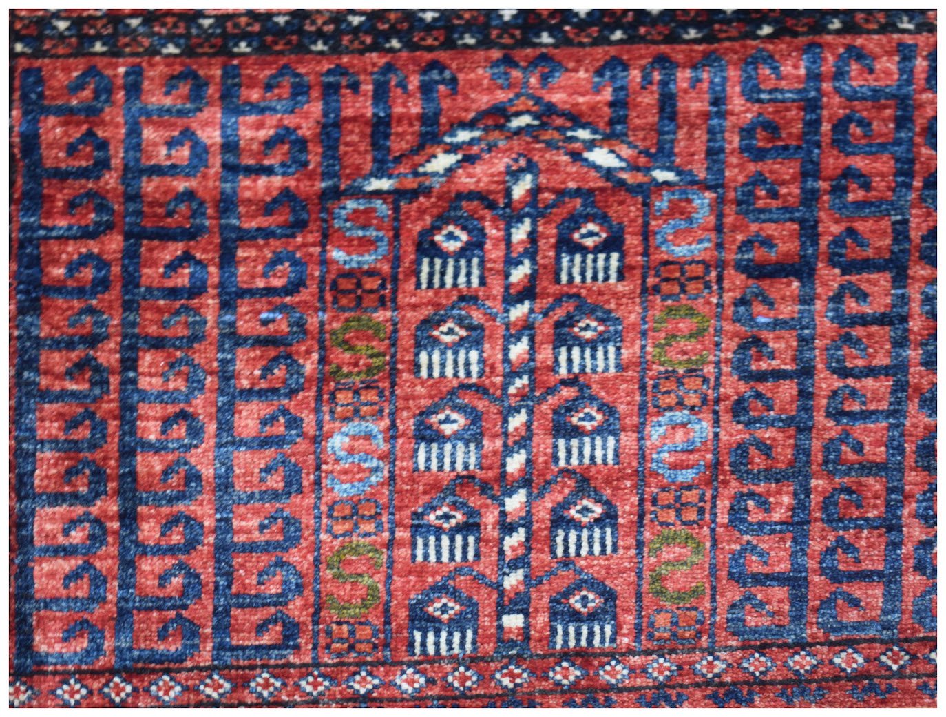A handmade Afghan Chobi rug featuring a traditional red and blue geometric Engsi pattern.