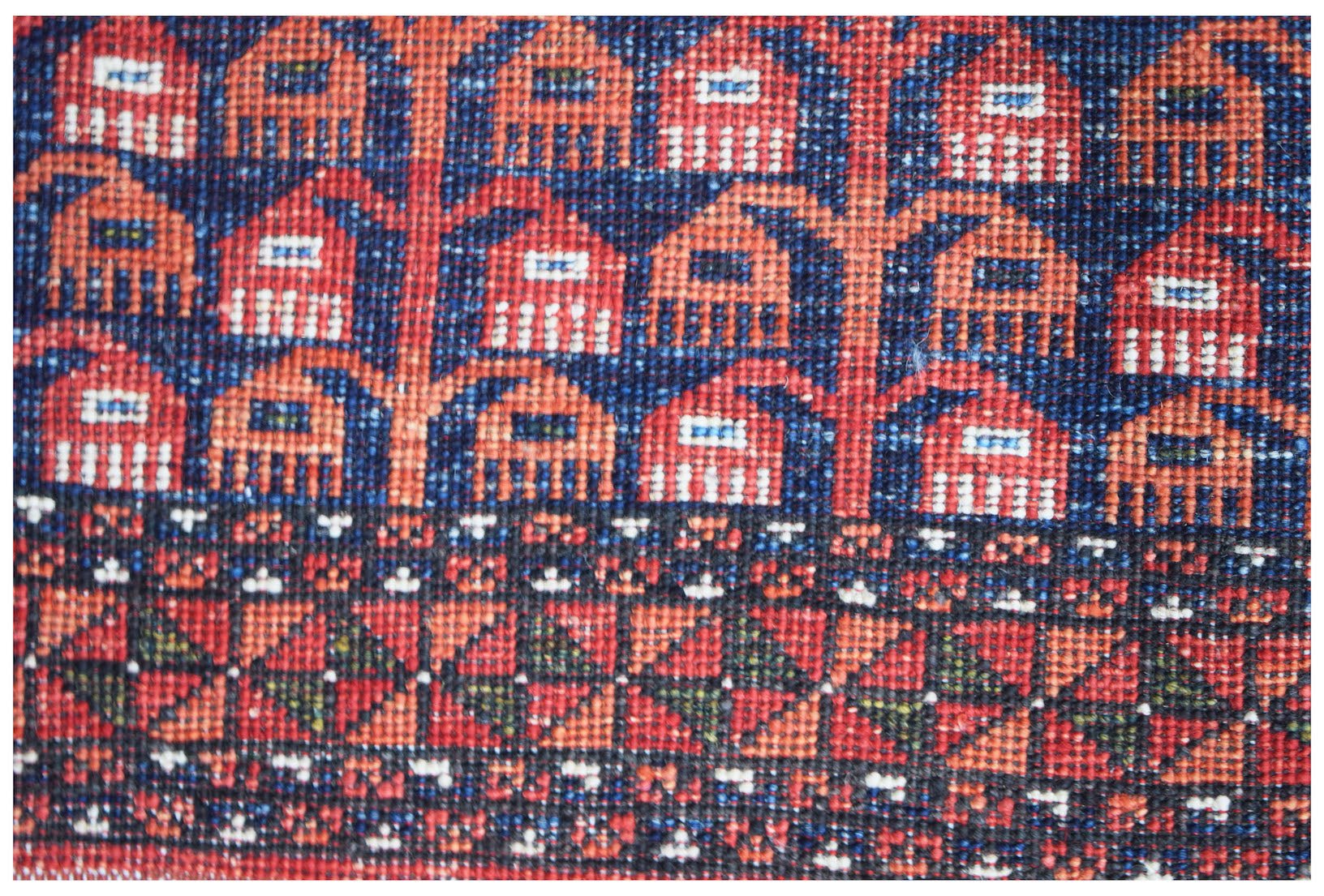A close-up of an Afghan Chobi rug featuring intricate geometric patterns in red, blue, and ivory.