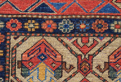 A close-up of an Afghan Chobi rug featuring intricate geometric patterns in red, blue, and ivory.