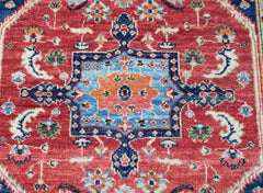 A handmade Afghan Chobi rug featuring a traditional Heriz pattern in red, blue, and orange tones.