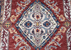 A handmade Afghan Chobi rug featuring a central diamond medallion in blue, red, and cream tones.
