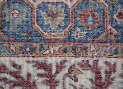 A close-up of a handwoven Afghan Chobi rug featuring intricate floral patterns in red and blue.
