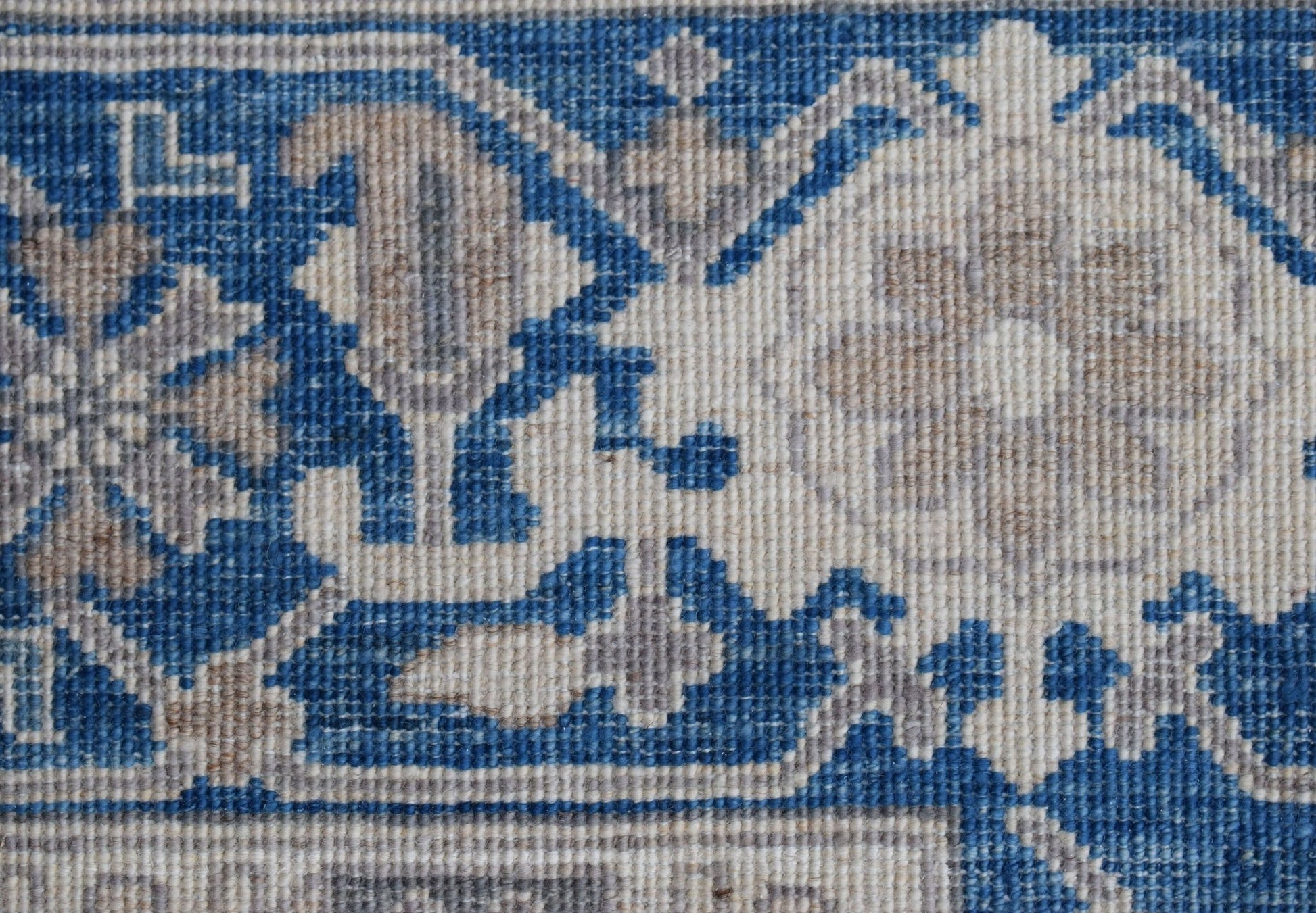 A close-up of a handwoven Afghan Chobi rug featuring a traditional blue and beige floral pattern.
