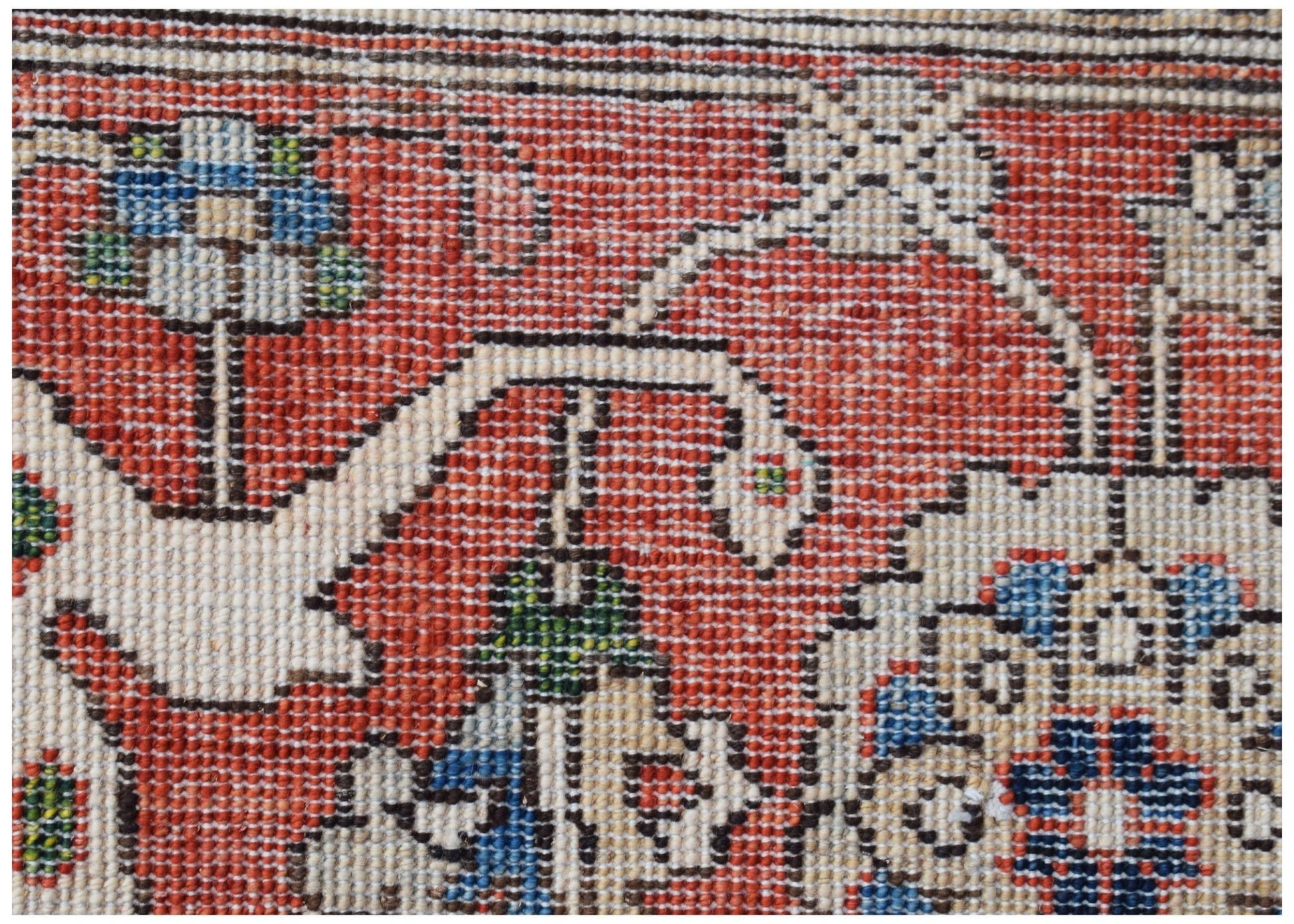 A close-up of a handwoven Afghan Chobi rug featuring traditional floral patterns in red and blue.