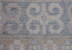 A close-up of a handwoven Afghan Chobi rug featuring blue pomegranate motifs on a beige wool base.