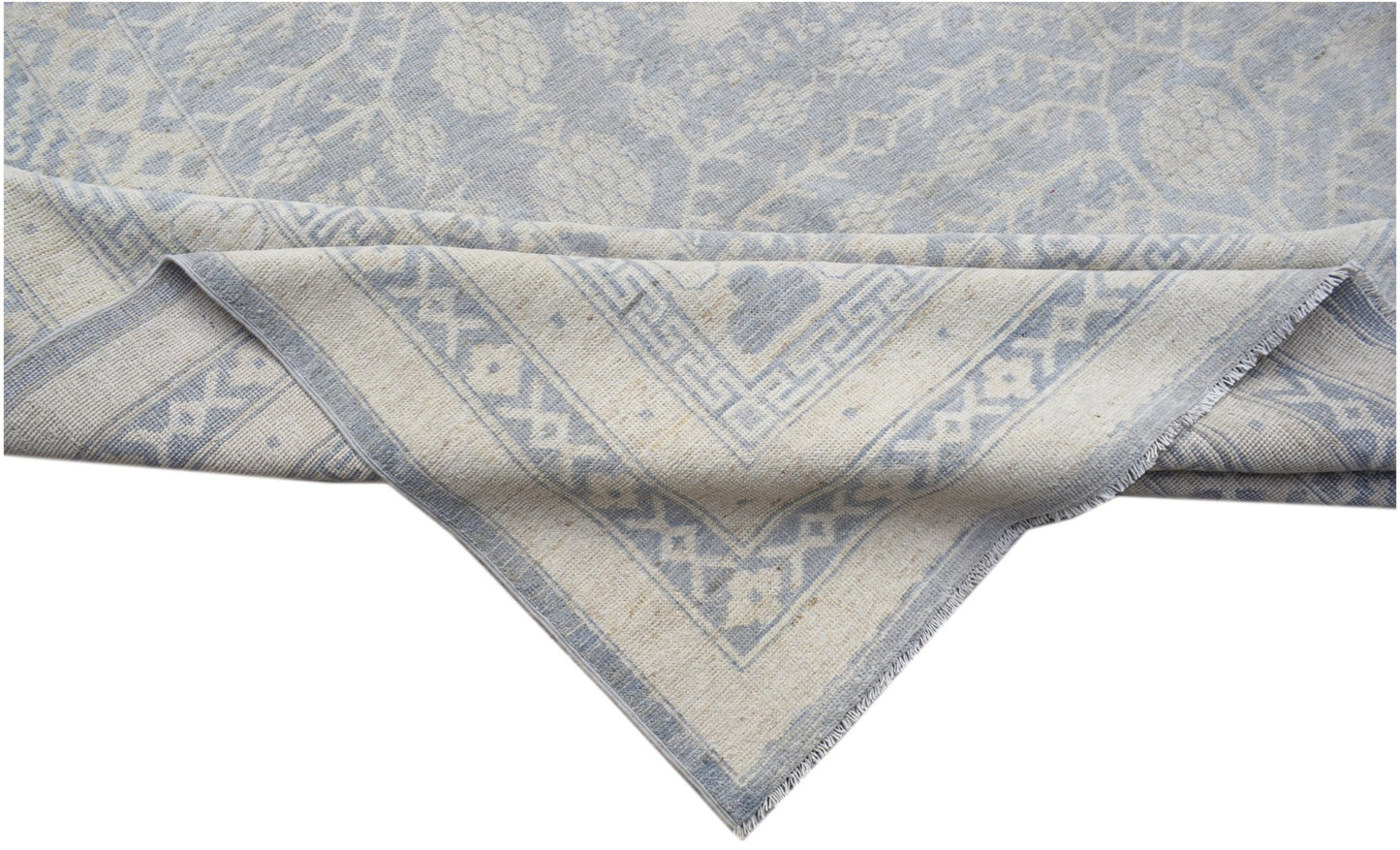 A handwoven Afghan Chobi rug featuring a light blue and cream floral pattern with a geometric border.