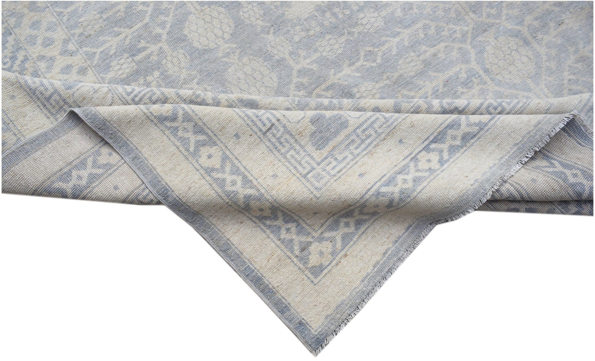 A handwoven Afghan Chobi rug featuring a light blue and cream floral pattern with a geometric border.