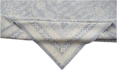 A handwoven Afghan Chobi rug featuring a light blue and cream floral pattern with a geometric border.