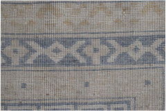 A handwoven Afghan Chobi rug featuring a geometric border pattern in blue and beige tones.