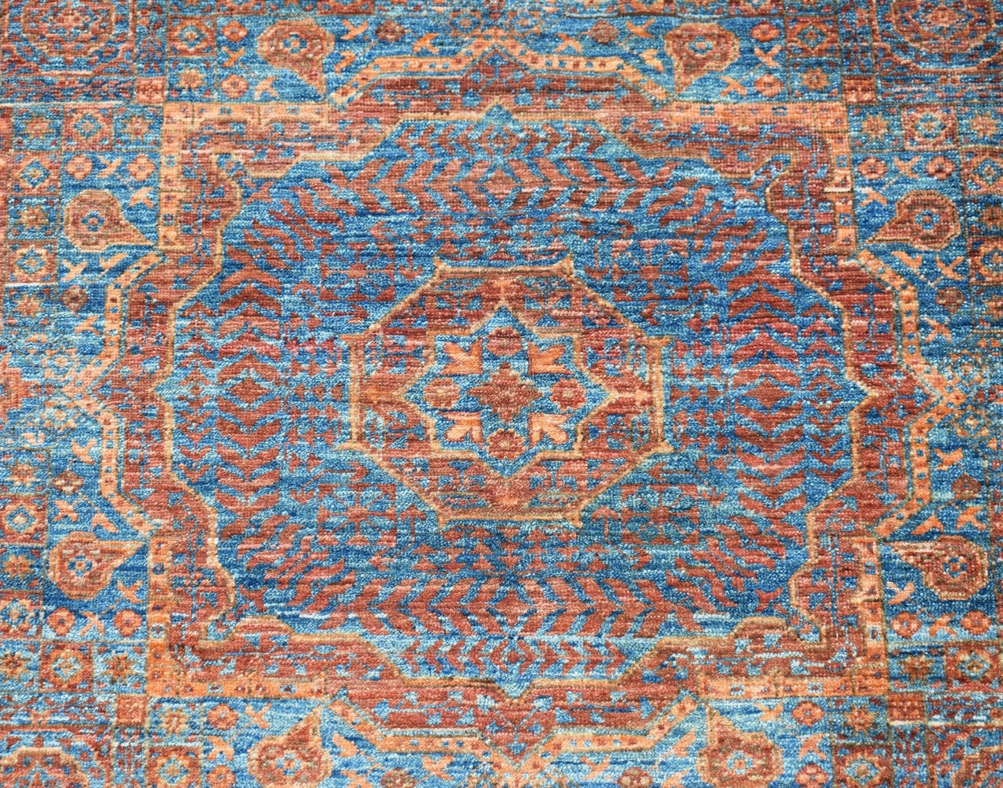 A handmade Afghan Chobi rug featuring a detailed blue and rust-colored Mamluk medallion pattern.