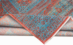 A handmade Afghan Chobi rug with a blue and red Mamluk pattern and a folded corner.