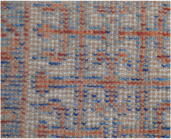 A close-up of a handmade Afghan Chobi rug featuring a geometric grid pattern in blue and orange.