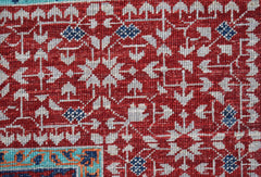 A close-up of a handmade Afghan Chobi rug featuring a detailed red and white Mamluk pattern.