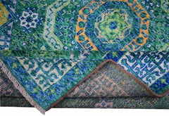 A handmade Afghan Chobi rug featuring a complex green and blue geometric medallion pattern.