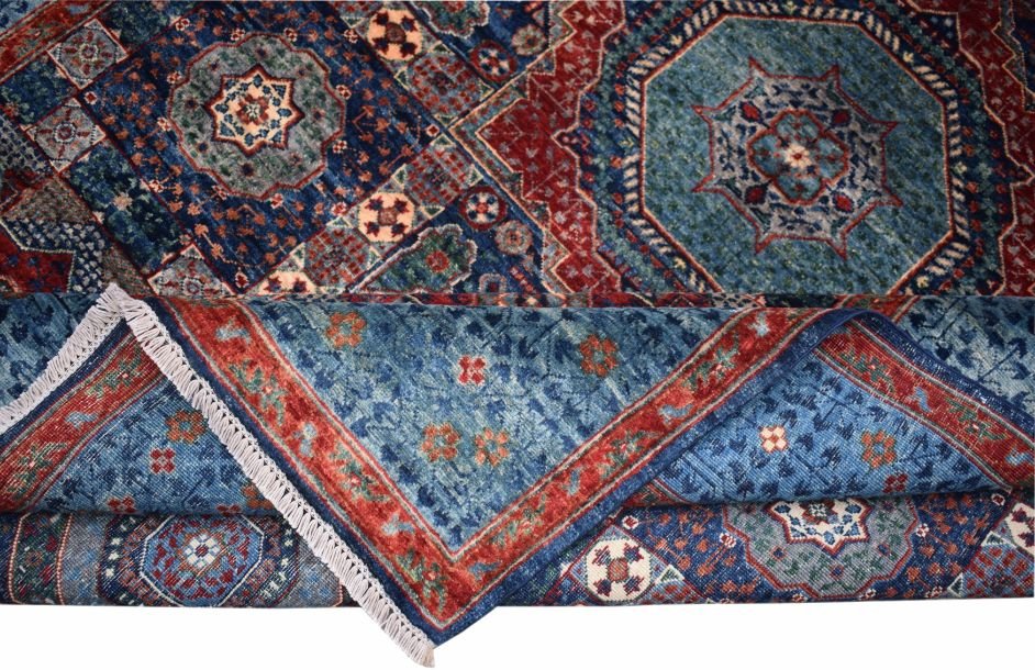 A handmade Afghan Chobi Mamluk rug featuring intricate geometric medallions in blue and red.