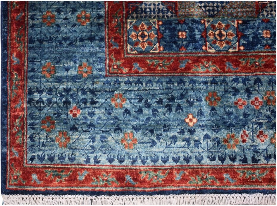 A handmade Afghan Chobi rug featuring a blue field with red borders and intricate floral motifs.