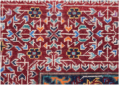 A close-up of a handmade Afghan Chobi rug featuring intricate geometric floral patterns in red.