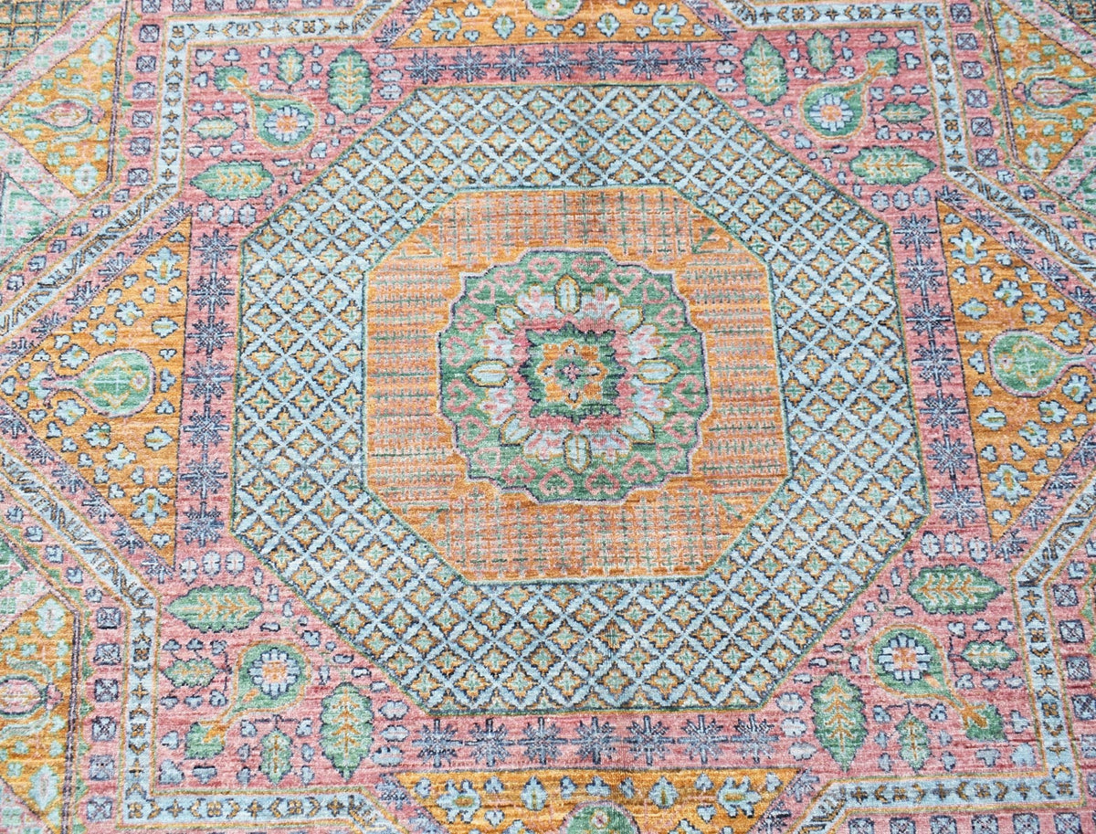 A handwoven Afghan Chobi rug featuring a geometric Mamluk pattern in soft orange, pink, and green.
