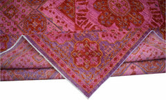 A handmade Afghan Chobi rug featuring a vibrant pink and red Mamluk medallion pattern.