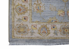 A handmade Afghan Chobi rug featuring a light blue field with floral patterns and a cream border.