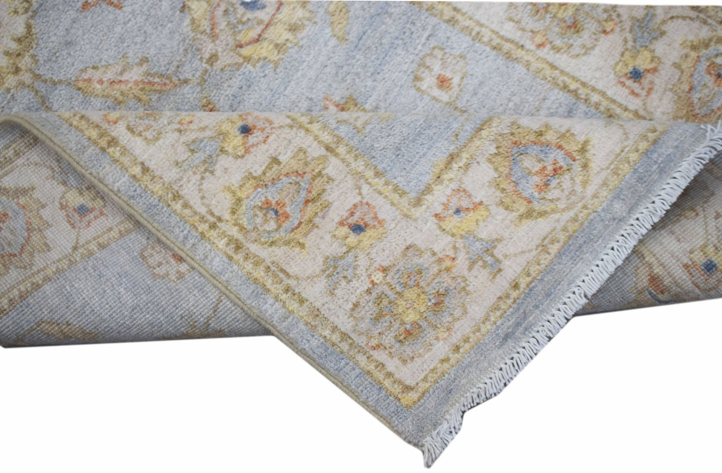A handwoven Afghan Chobi rug featuring a traditional floral pattern in soft blue and beige tones.