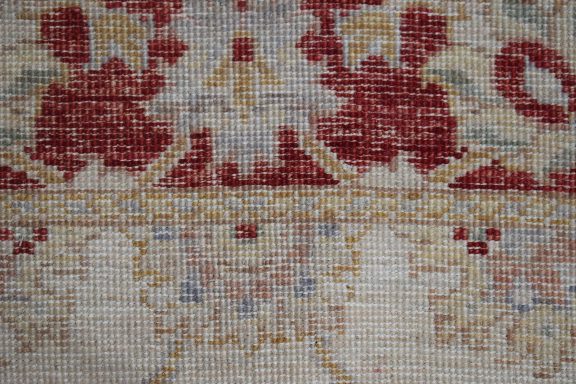 A close-up of a handwoven Afghan Chobi rug featuring traditional floral patterns in red and beige.