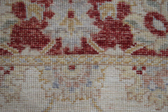 A close-up of a handwoven Afghan Chobi rug featuring traditional floral patterns in red and beige.