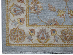 A handwoven Afghan Chobi rug featuring a traditional floral pattern in soft blue and earthy tones.