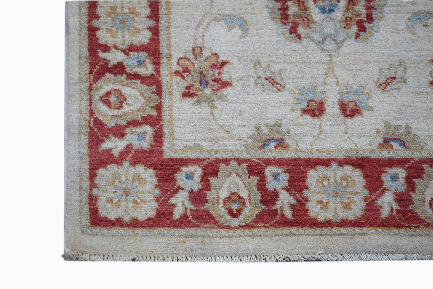 A handmade Afghan Chobi rug featuring a red floral border on a cream background.